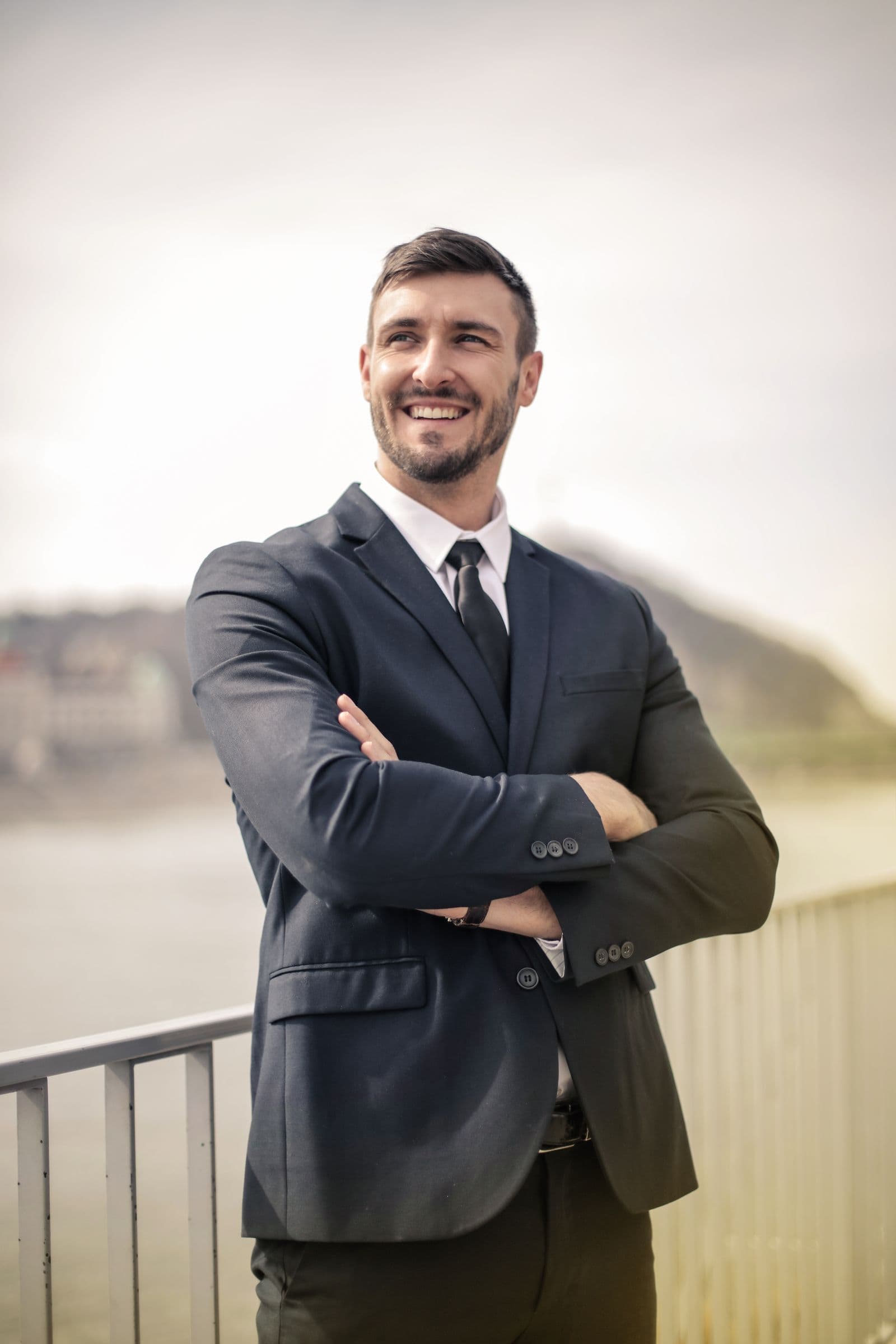 A confident man in a dark suit with a strong, bright smile